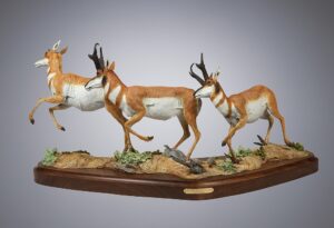 Bronze sculpture by Fred Boyer of a doe being followed by two deer bucks