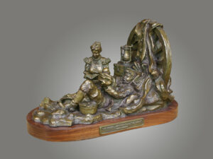 bronze sculpture by Scott Rogers of a mother reading a bible to her children. The work is mounted on a wooden base