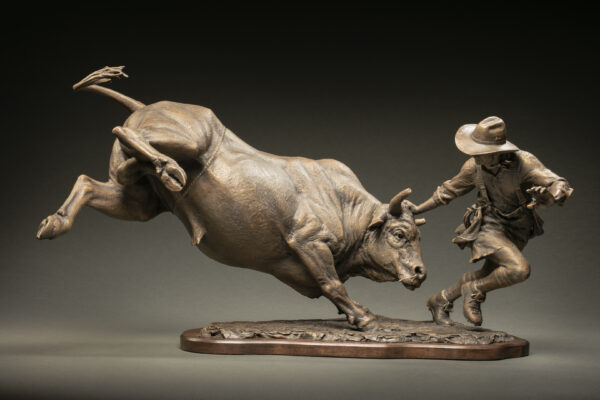 Bronze sculpture of a bull chasing a cowboy