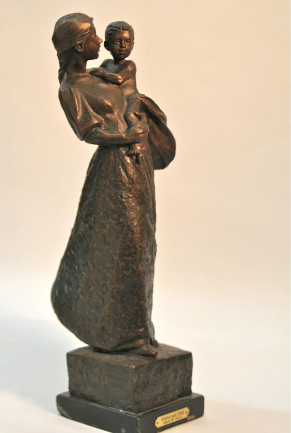 Standing female in long skirts gazing at her baby she is holding on her hip.