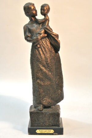 Standing female in long skirts gazing at her baby she is holding on her hip.