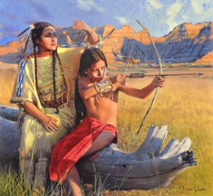 A Western realist painting titled 'Coming Of Age' by David Yorke. Sitting on a large, weathered log in a golden field, an Indigenous woman in a traditionally decorated yellow dress with hair feathers proudly watches a young boy with face paint. The boy, wearing a red wrap and a beaded arm guard, is drawing back a bow and arrow to aim. In the sunny background, horses graze before a massive red-orange canyon under a bright sky.